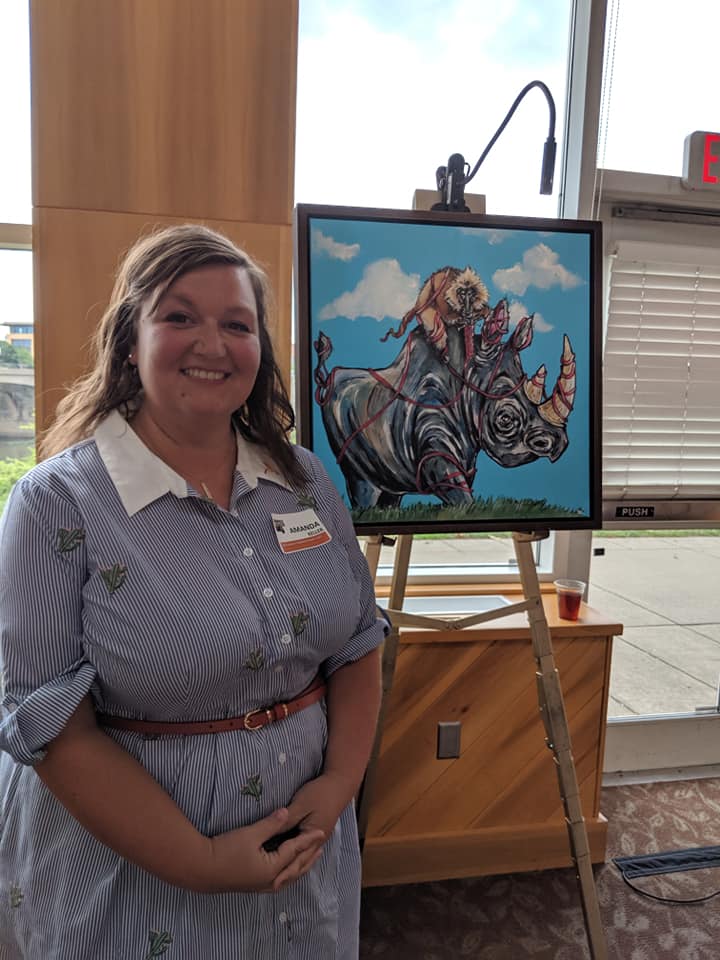Amanda Keller standing beside animal artwork on an easel