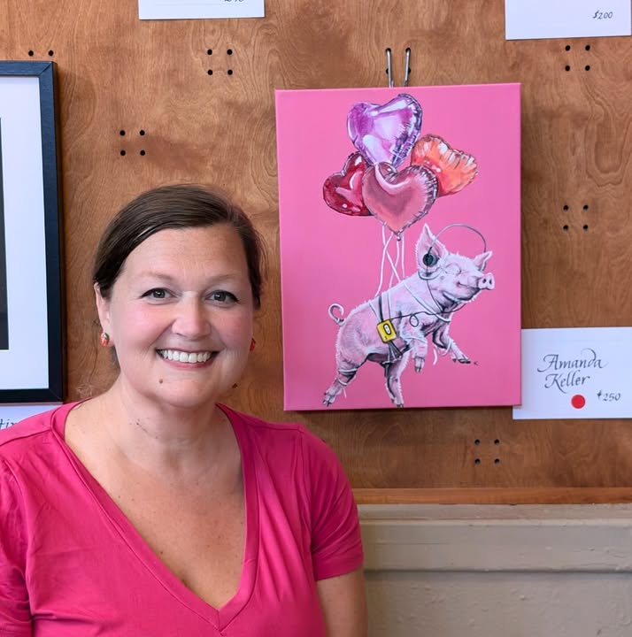 Amanda Keller beside a pink pig illustration at an art display